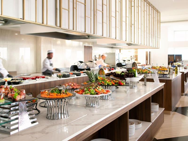 Buffet mit vielfältigen Speisen, helle Holzoberflächen und Steckdosen an der Theke.