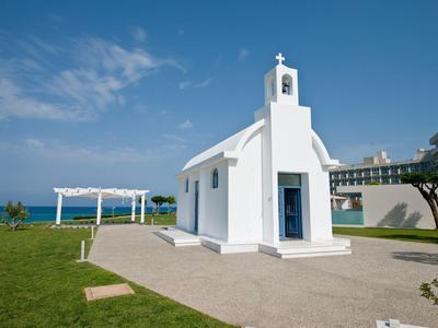 Kleine witte kapel met blauwe zee op de achtergrond onder een heldere hemel.
