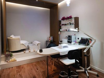 Modern ingerichte schoonheidsruimte met behandeltafel, stoelen en grote spiegels.