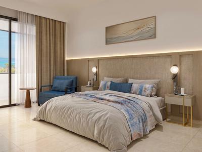 Modern hotelkamer met groot bed, blauwe stoelen en lichte houten vloer.