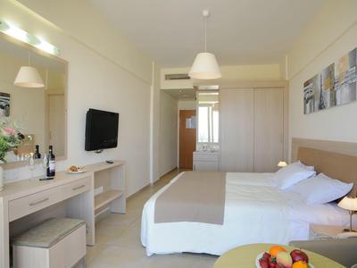 Modern hotelkamer met tweepersoonsbed, bureau, tv en lichte inrichting.