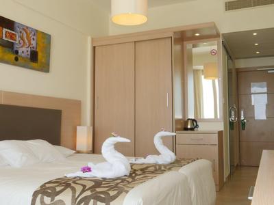 Moderne hotelkamer met tweepersoonsbed, handdoekzwanen en kleine werkruimte.