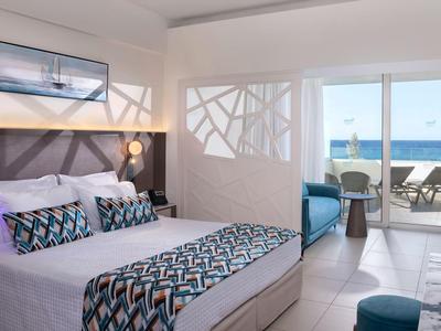 Modernes Hotelzimmer mit Doppelbett und Meerblick von der Terrasse.