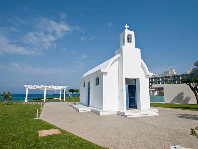 Kleine witte kapel met blauwe zee op de achtergrond onder een heldere hemel.