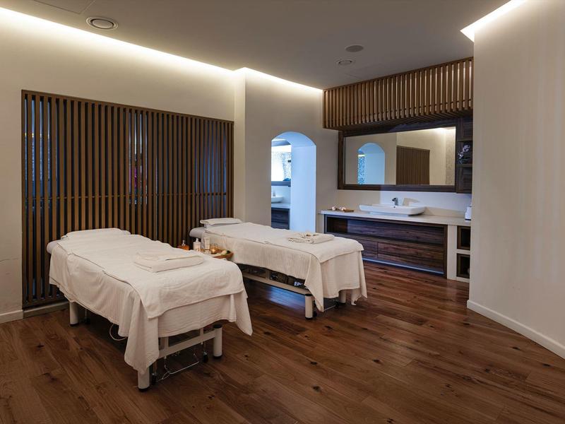 Moderne wellnessruimte met twee massagetafels en warme houten vloer.