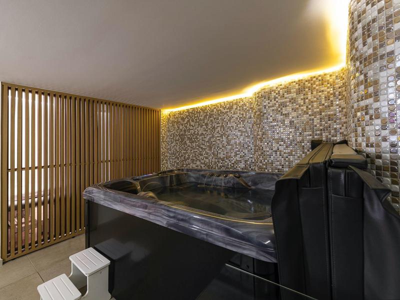 Moderne hot tub met mozaïektegels en sfeerverlichting in een wellnessruimte.