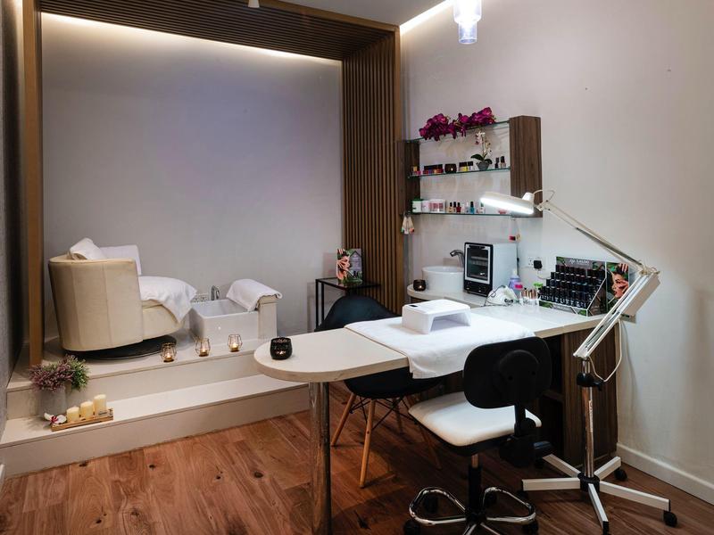 Modern ingerichte schoonheidsruimte met behandeltafel, stoelen en grote spiegels.