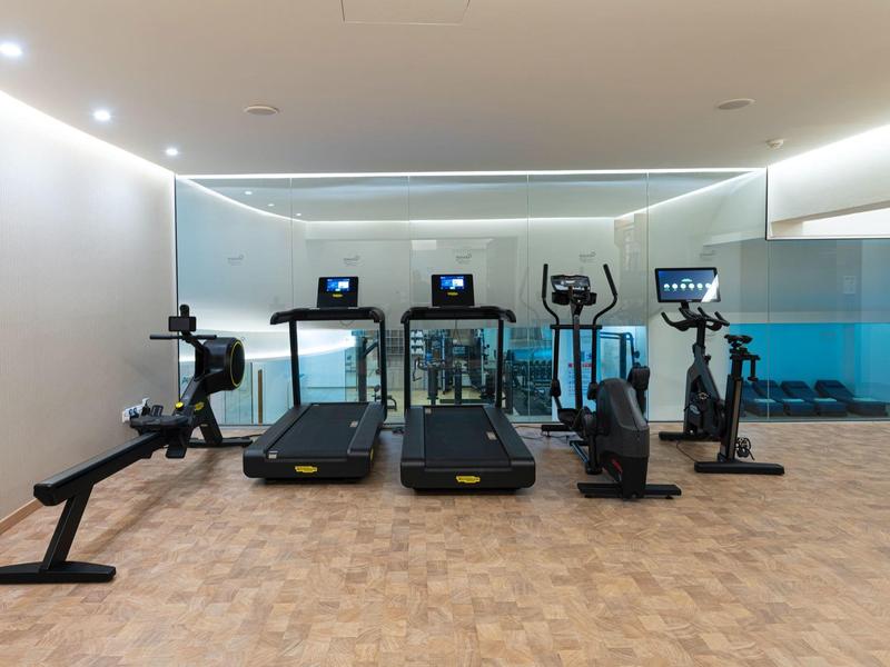 Moderne sportschool met roeimachine, loopbanden, crosstrainers en hometrainers voor glazen wand.