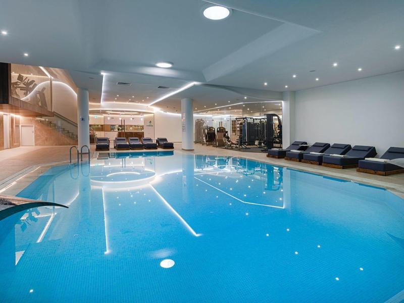 Moderne binnenzwembad met comfortabele ligstoelen in een lichte wellnessruimte.