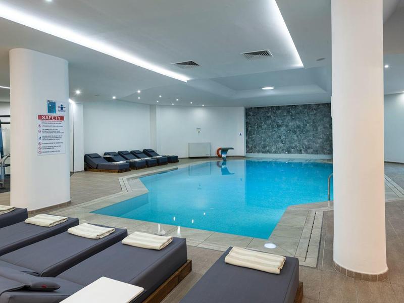 Moderne binnenzwembad met ligstoelen en zachte verlichting in een wellnessruimte.