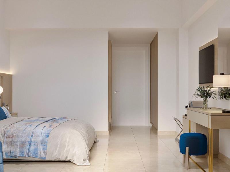 Lichte hotelkamer met bed, bureau en stoel in neutrale kleuren.