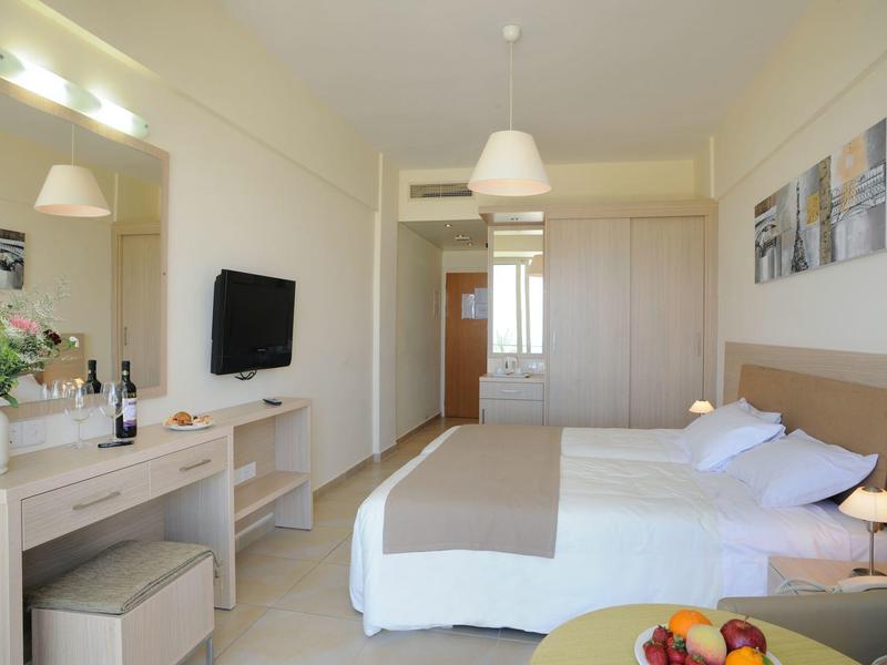 Modern hotelkamer met tweepersoonsbed, bureau, tv en lichte inrichting.