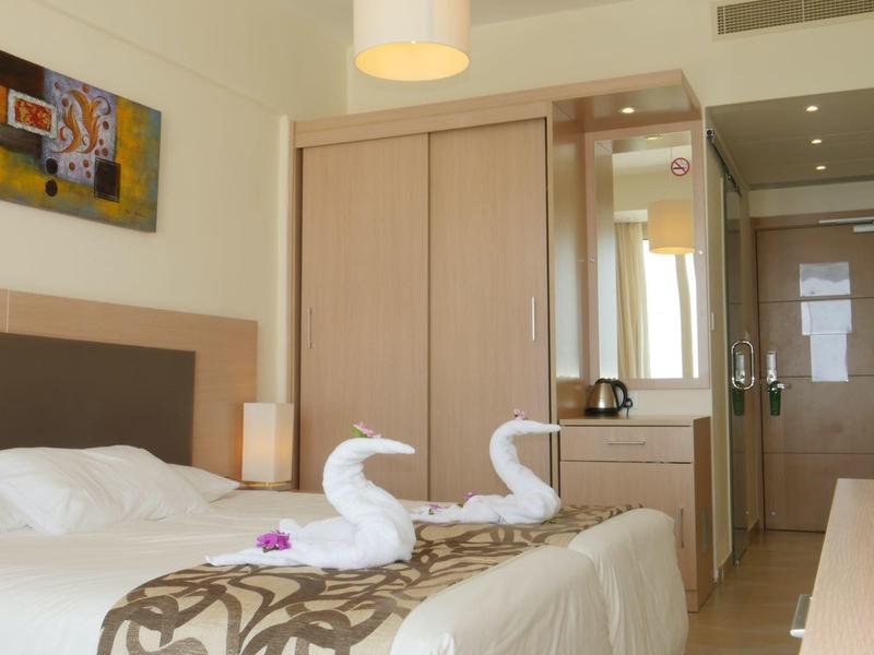 Moderne hotelkamer met tweepersoonsbed, handdoekzwanen en kleine werkruimte.