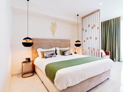 Camera moderna con letto grande, copriletto verde, lampade sospese e tende vicino alla finestra.