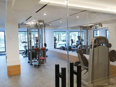 Palestra moderna con varie attrezzature e grandi finestre per la luce naturale.