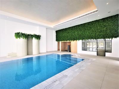 Piscina interna moderna con superficie dell'acqua blu e decorazione murale verde in una stanza luminosa