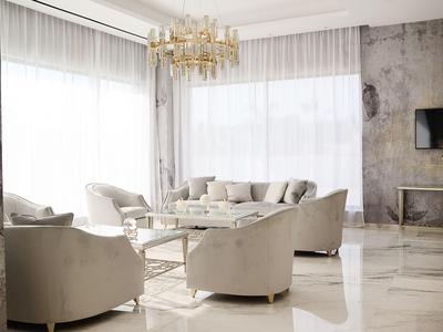 Soggiorno elegante con poltrone crema, divano, pavimento in marmo e grande lampadario.