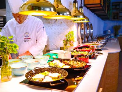 Cuoco in abbigliamento bianco prepara una varietà di piatti in una cucina moderna.