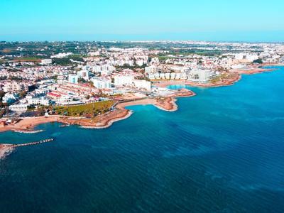 Città costiera con scogliere, spiagge sabbiose e molti edifici vicino all'acqua sotto un cielo sereno.