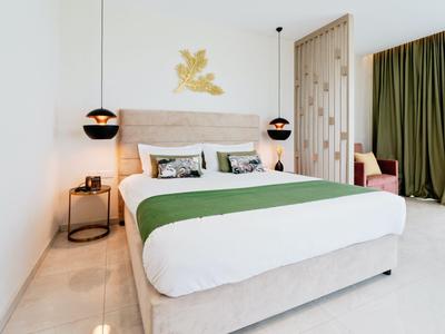 Camera moderna con letto grande, copriletto verde e tende, decorazione murale dorata