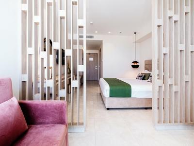 Camera d'hotel moderna con letto ergonomico, copriletto verde e divisorio verticale