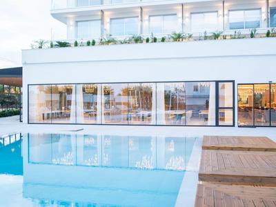 Hotel moderno con grande piscina e facciata in vetro alla luce del giorno.