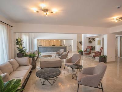 Großzügiger, moderner Wohnraum mit beige Polstermöbeln, schwarzen Tischen und heller offener Küche.