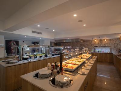 Moderner Frühstücksbereich mit Buffet in einem Hotel mit warmem Holzdekor und vielfältiger Auswahl.