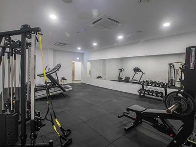 Modernes Fitnessstudio mit verschiedenen Trainingsgeräten und Spiegelwand