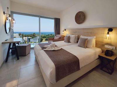 Modern eingerichtetes Hotelzimmer mit Doppelbett, Meerblick und Balkon.