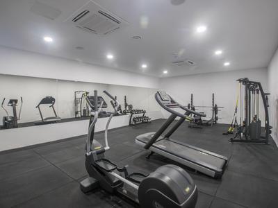 Moderner Fitnessraum mit Laufbändern, Fahrrädern und Kraftgeräten, weiße Wände und Spiegel.