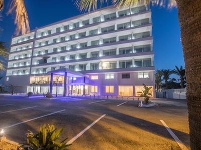 Modernes Hotelgebäude bei Nacht mit beleuchteten Balkonen und Eingangsbereich.