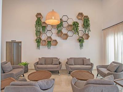 Moderner Aufenthaltsraum mit grauen Sesseln, hölzernen Couchtischen und Wanddekoration mit Pflanzen.