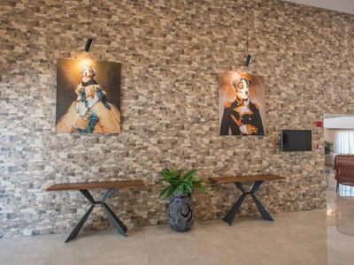 Moderner Empfangsbereich mit Steintapete, Holztisch und dekorativen Bildern an der Wand.