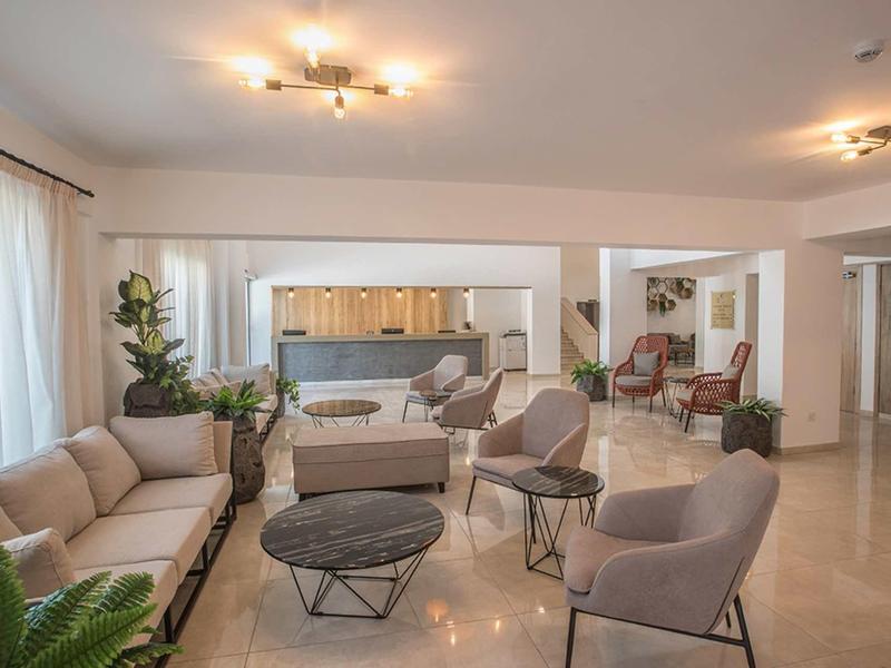 Großzügiger, moderner Wohnraum mit beige Polstermöbeln, schwarzen Tischen und heller offener Küche.