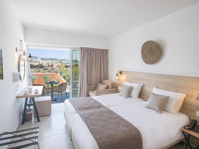 Helles Hotelzimmer mit Doppelbett, Balkon, Stadtblick und modernem, minimalistischem Design.