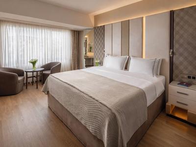 Elegantes Hotelzimmer mit großem Bett, Sitzbereich und weichem Licht.