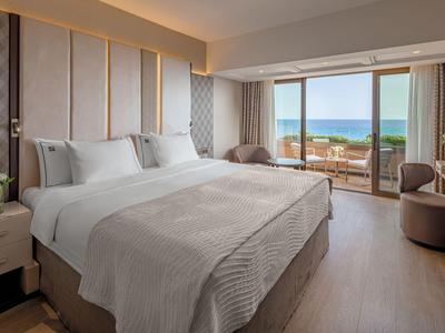 Modernes Hotelzimmer mit Doppelbett und Meerblick durch große Fenster.