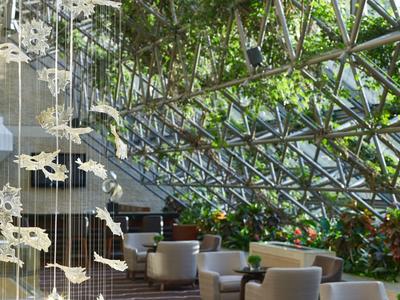 Interior moderno de hotel con grandes ventanas de vidrio y áreas de asiento cómodas.