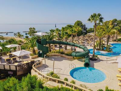 Zona de piscina con tobogán de agua, piscina infantil, sillas de descanso y vista al mar en un día soleado