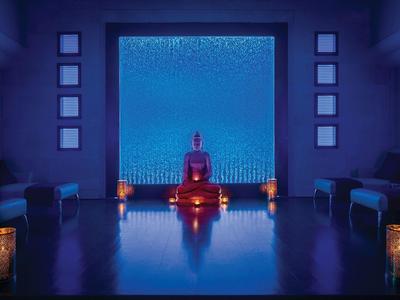 Dim meditation room with Buddha statue, candles, and blue accent lighting