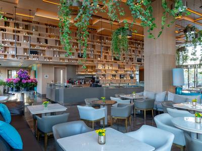 Modern eingerichteter Hotelbarbereich mit hängenden Pflanzen und gemütlichen Sitzgelegenheiten.