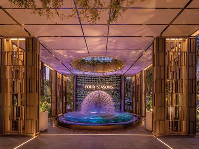 Moderner Hoteleingang mit stilvollem Brunnen und Glasdecke bei Dämmerung.