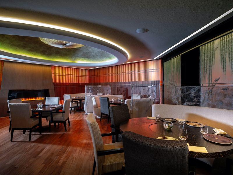 Elegant hotel restaurant with round tables, comfortable chairs, and modern lighting.