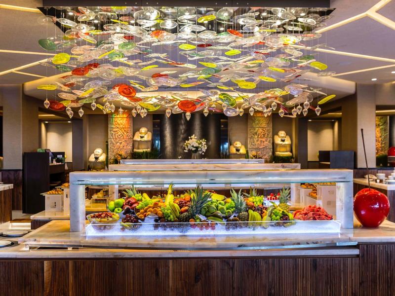 A modern buffet area with various dishes and colorful ceiling decorations in a hotel restaurant.