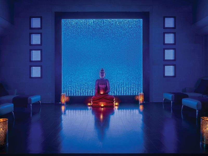 Dim meditation room with Buddha statue, candles, and blue accent lighting