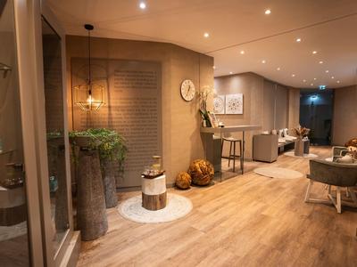 Helles Wohnzimmer mit Holzfußboden, modernen Möbeln und dekorativen Pflanzen in warmem Licht.