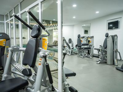 Équipements de fitness modernes dans une salle de sport lumineuse et spacieuse avec des murs en verre.