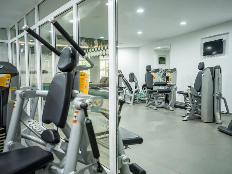 Moderne Fitnessgeräte in hellem, sauberem Trainingsraum mit großen Fenstern und Spiegeln.