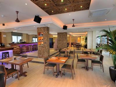 Moderner Restaurantraum mit Holzstühlen, Tischen, Steinsäulen und indirekter Beleuchtung.